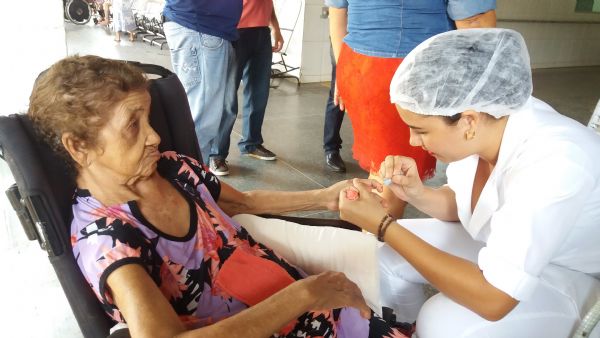 A enfermeira Fernanda Caroline pintando as unhas de uma idosa do Abrigo Bom Jesus