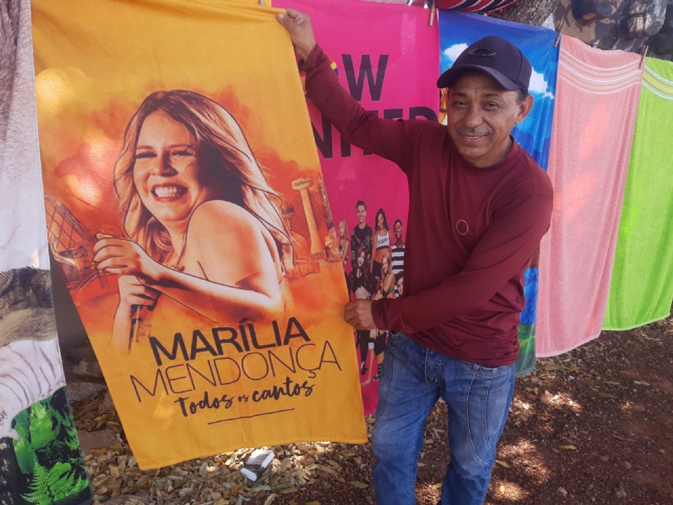Vendedor faz sucesso com toalhas de cantores sertanejos em VG: 'da Marlia Mendona sai muito'