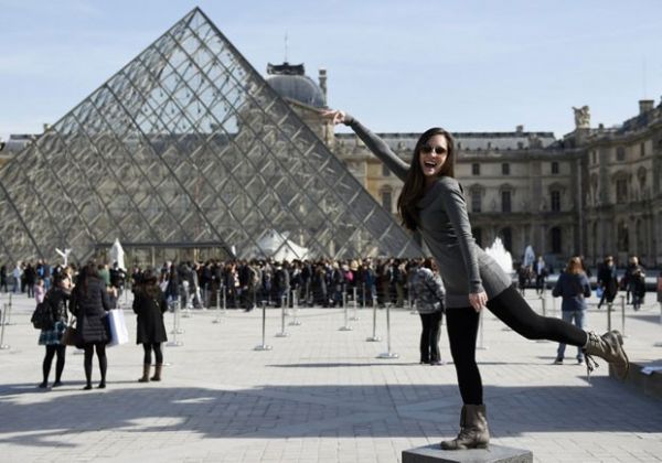Turista posa para foto em frente  pirmide do Museu do Louvre, em Paris